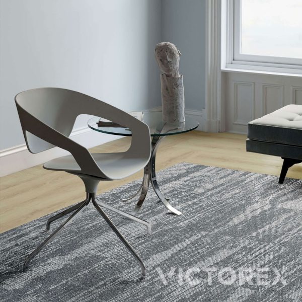Interface Works Stream carpet tile in Granite colour, in a living room with a chair and side table; Monolithic layout.